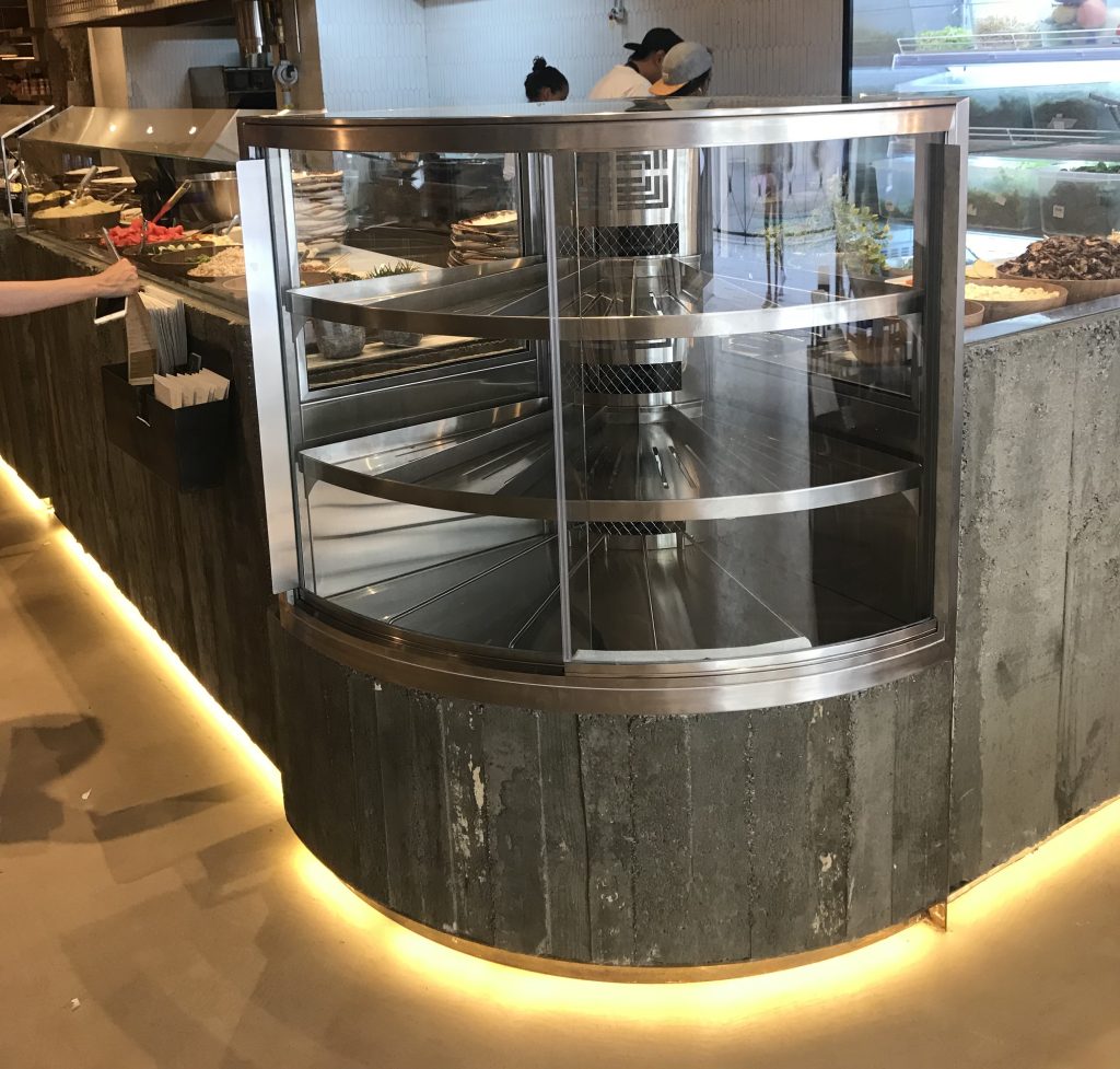 vitrina que hace una curva de 90 grados y que tiene puertas correderas que se abren haciendo la forma de la curvatura de la vitrina